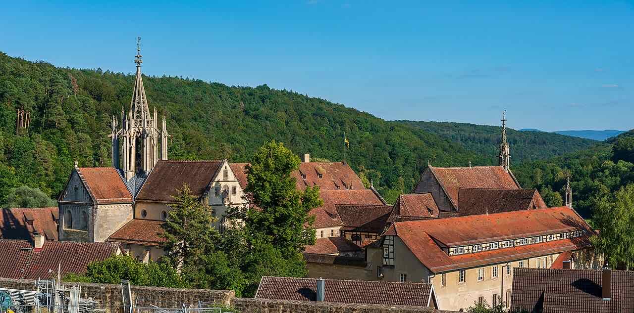 Kloster Bebenhausen with its slim church spire and red roofs, set against forested hills