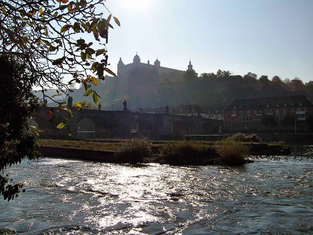 The Old Main Bridge with its saint statues and the Marienberg fortress above it, against the evening sun